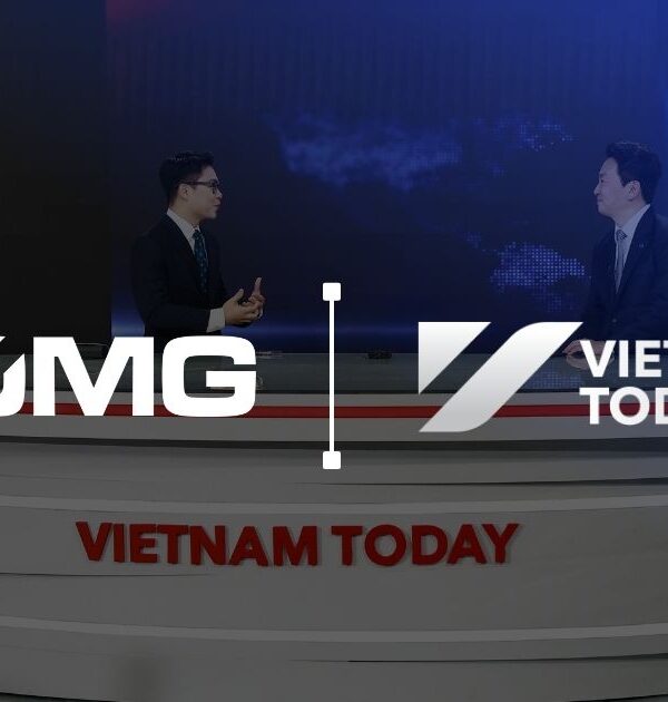 Two male news anchors sit at a circular multi-tiered desk branded 'VIETNAM TODAY' in a blue news studio with a world map backdrop and flags (South Korea and Vietnam).